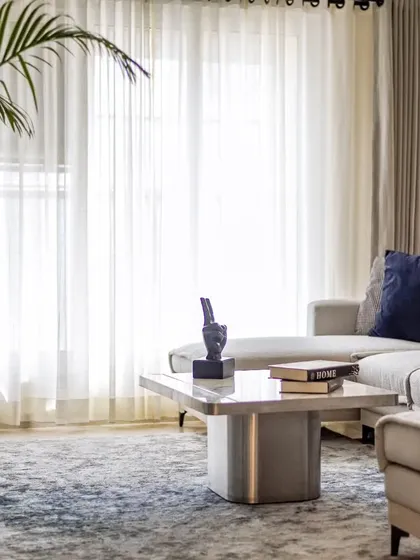 The living room is a symphony of comfort and style. The large grey sofa, custom marble coffee table, and plush rug create a sanctuary for relaxation and visual poetry.