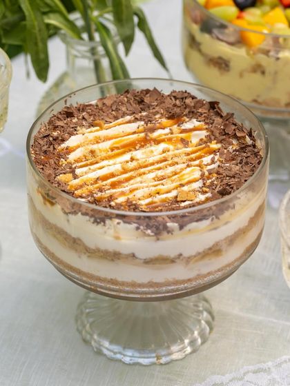 My Banoffee dessert, the WisQ way. It features a golden biscuit base, my house-made caramel, fresh banana slices, and light cream, drizzled with more caramel.