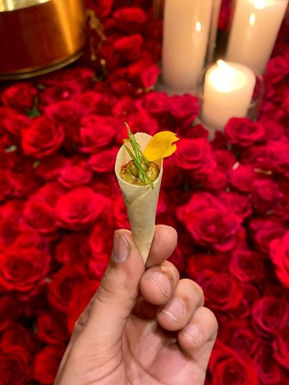 Our Wild Mushroom & Truffle Galouti Cornet, a signature canapé, held against the stunning backdrop of red roses. A perfect start to a sensational meal.