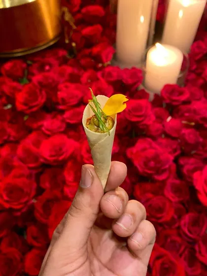Our patented Wild Mushroom & Truffle Galouti Cornet, a sophisticated and flavorful canapé served against a backdrop of red roses at an intimate dinner party.