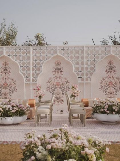 A palatial wedding setup in Jaipur with a soothing pastel and ivory color palette. The backdrop features hand-painted Mughal-inspired motifs, creating a look of contemporary royalty.