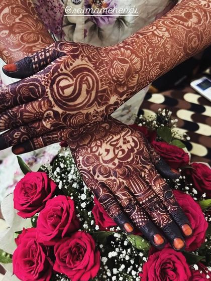 A personalized design with the initial 'S' after the henna paste has been removed. The dark stain looks beautiful against the bouquet of red roses.
