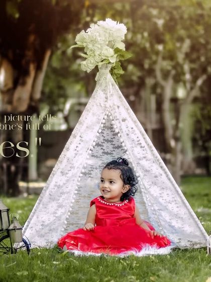 Every picture tells a story, and this one's full of giggles. A girl in a red dress smiles in her outdoor teepee setup.