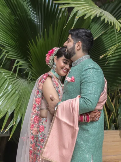 A warm and affectionate embrace between the couple, set against a backdrop of tropical foliage. This intimate portrait highlights their close bond and happiness.