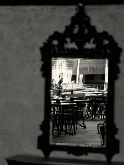 A reflection of the bar's seating area in a dark, intricately framed mirror, creating a picture within a picture.