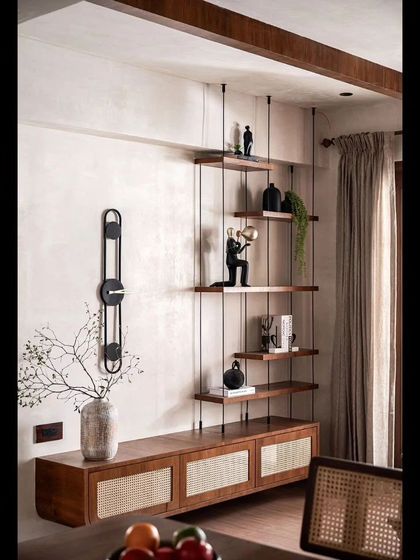 A custom-designed shelving unit with suspended wooden shelves creates a light and airy storage solution in the living room.