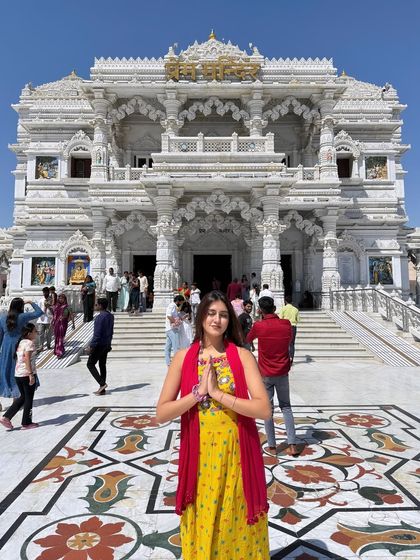 A respectful pose with hands joined in 'namaste' at Prem Mandir. The grandeur of the temple complements the traditional outfit.