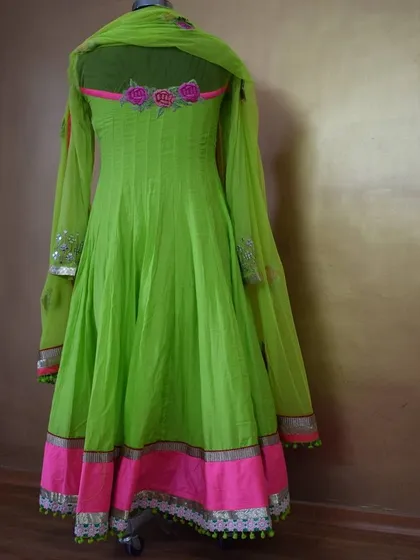 The back view of the vibrant green Anarkali, highlighting the sheer sleeves and the floral embroidery detail on the upper back.