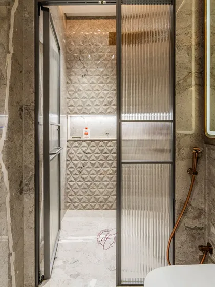 The fluted glass shower partition with its sleek dark frame is a contemporary design element that offers privacy while keeping the space feeling open.