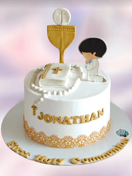 A serene and elegant cake for a First Holy Communion. The design features a Bible, rosary beads, and a chalice, all in white and gold.