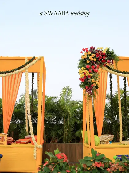 A bright and sunny Haldi setup with yellow canopies, marigold garlands, and colorful floral arrangements, creating a classic and cheerful ambiance.