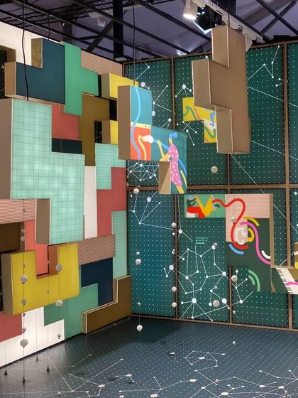 Another view of the 'Solo Commerce' installation, showing the interplay of the floating illustrated blocks. The design creates a dynamic and colorful environment that visualizes the global digital network enabling this new way of working.