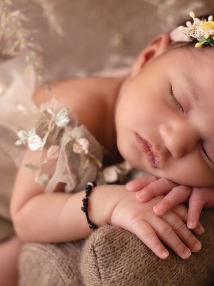 Love rests softly in these little moments. A close-up shot of a baby in a beautiful floral headband, peacefully asleep.