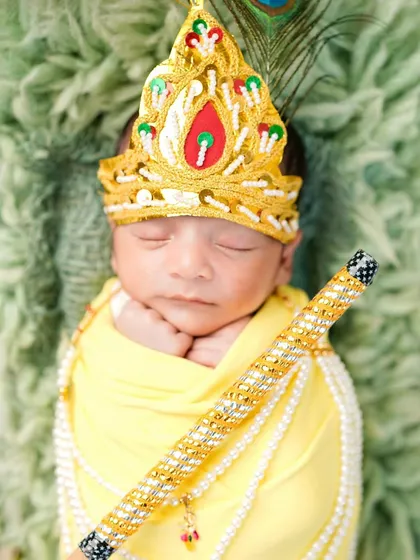 A close-up of a newborn dressed as baby Krishna, complete with a beautiful crown and flute. Even the tiniest babies can be part of our magical Janmashtami sessions.
