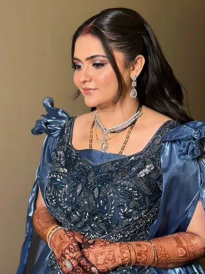 A side profile of the bride in her blue reception gown. The soft curls and glowing makeup create a look of pure elegance.