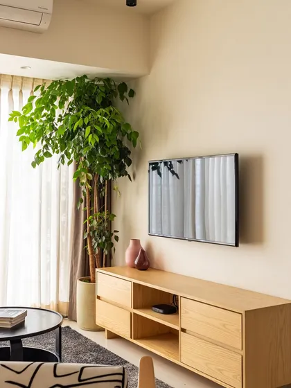 The simple, light wood TV console provides ample storage while maintaining the room's minimalist aesthetic.