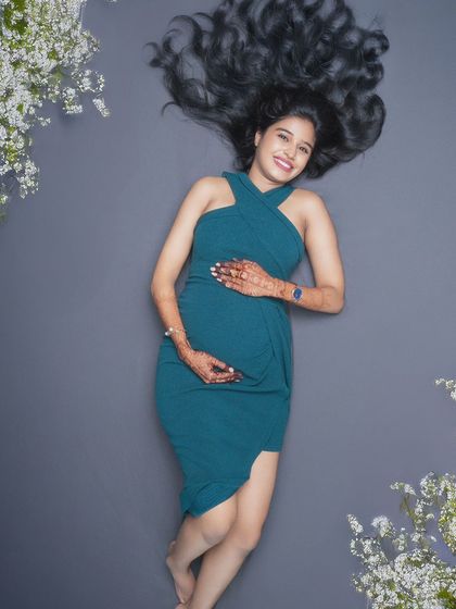 Embracing the beauty of new beginnings. This serene shot captures the peaceful anticipation surrounding motherhood, with a simple dress and floral accents.