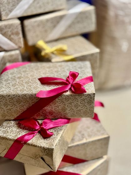 A stack of beautifully wrapped gift boxes, showcasing the different ribbon colors chosen by a client for their event. We love bringing a personalized touch to every order.