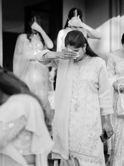 A candid black and white photo capturing the emotional 'vidaai' ceremony, where the bride's family tearfully says goodbye. This raw, unposed moment is a powerful example of documentary wedding photography.