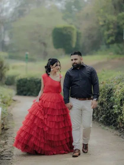 A candid moment within a cinematic shoot. As the couple walks hand-in-hand through a park path in Pune, her magnificent red dress adds a touch of drama to this otherwise natural interaction, blending two styles perfectly.