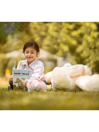 A quiet moment reading fairy tales in the park. For Brishka's seventh birthday shoot, we included her favorite book and teddy bears to capture her personality and interests at this age.