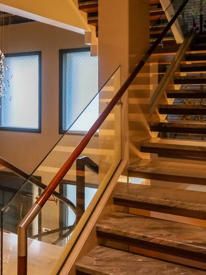 A staircase is a central feature that can transform a space. This design combines elegant marble treads, a wooden handrail, and a glass balustrade, enhancing the overall aesthetic of the home.