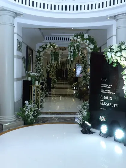 This entrance for a black-and-white themed event is the epitome of chic. A clean, minimalist welcome area is framed by lush white florals, creating a sophisticated and modern look.