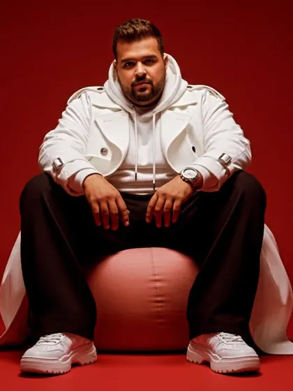 A modern, streetwear look against a bold red background. My style is always evolving, just like my music, which spans genres from Soul Techno to UK Punjabi.