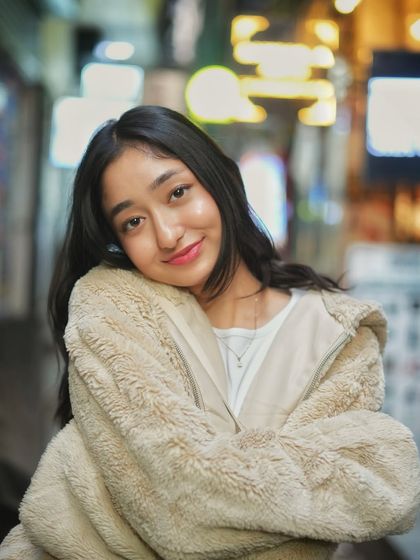 A relaxed and happy pose, leaning into her shoulder. This shot captures a moment of comfort and joy, with the city lights providing a warm, dreamy backdrop.