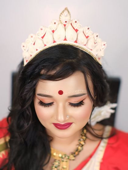 A serene close-up of a Bengali bride, her eyes closed, showcasing the traditional 'chandan' art on her forehead and the beautiful 'mukut'.