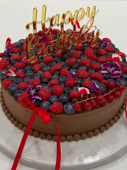 A beautiful shot of the 54% Belgian dark chocolate ganache cake made for Kanika Kapoor, topped with fresh summer berries and a "Happy Birthday" topper.