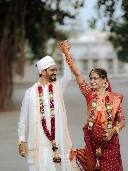 The couple celebrating after their wedding, holding hands and raising their arms in a gesture of triumph and joy.