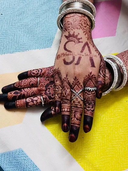 A close-up of the personalized initials on the back of the hand, now a beautiful deep brown. It’s a special touch for the bride.