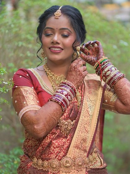 A close-up of the bride adjusting her earrings, showing the intricate details of her South Indian bridal look.