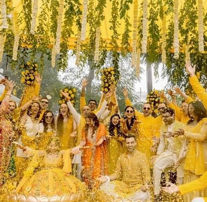 The quintessential Haldi moment, with the couple showered in flower petals by their friends and family under a canopy of hanging florals.