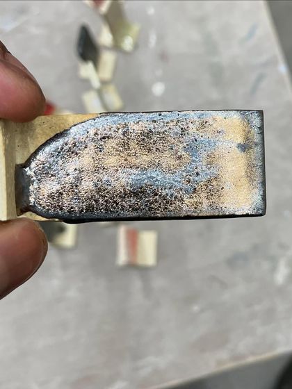 A glaze test tile showing a metallic, rustic finish. Testing glazes is like a science experiment; it's how I discover new palettes and textures for my work.