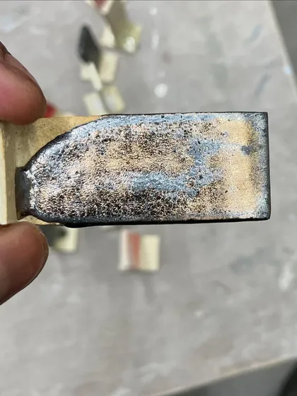 Another glaze test, this time resulting in a metallic, cratered surface. The chemistry of ceramics is full of wonderful surprises.