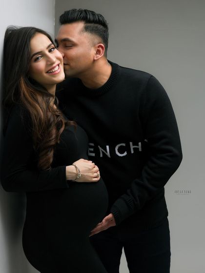 A tender kiss on the cheek captured in a beautiful black and white maternity photo. The focus is entirely on their love and happiness.