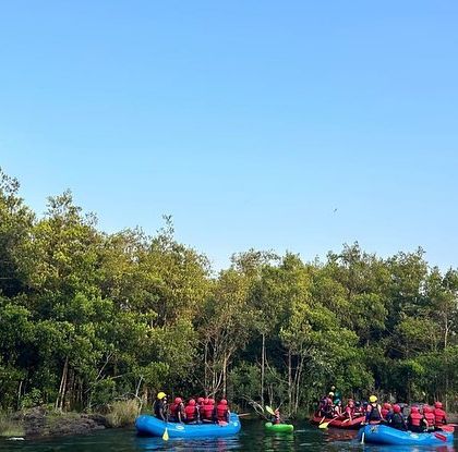 Two rafts full of campers float near the lush riverbank, taking in the serene natural surroundings.