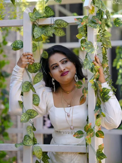 A creative portrait with the subject framed by a white ladder and green vines. We use props and angles to create visually interesting photos.