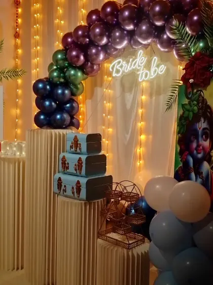 A closer view of the Radha-Krishna themed bride-to-be decoration. The plinth stands are decorated with stacked suitcases and a mini Ferris wheel.