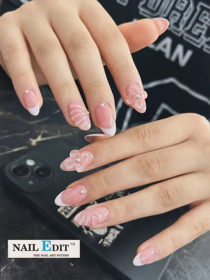 Perfect for a beachy or mermaid-inspired theme, this set combines a classic French manicure with intricate 3D seashell and flower sculptures. The delicate rhinestones add a touch of sparkle to the translucent, sculpted elements on these almond-shaped extensions.