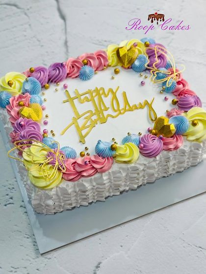 A vibrant and colorful trending sheet cake, decorated with a rainbow of pastel rosettes.