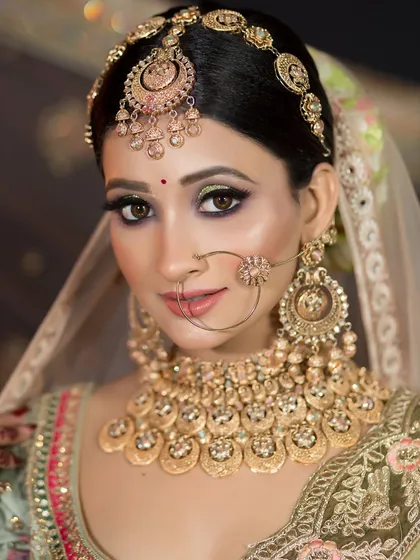A close-up of the bride in the pastel green lehenga, showing the detail of the green and gold eye makeup.