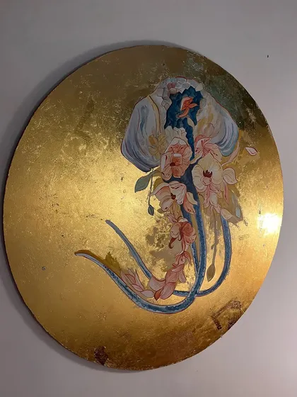 The finished jellyfish artwork, a circular canvas where a translucent sea creature adorned with flowers floats on a sea of gold leaf. This piece is designed to be a luxurious, imaginative focal point.
