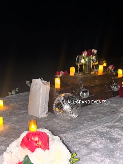 Our team meticulously arranges every detail for a night-time beach proposal. Here you can see the placement of dozens of electric candles to ensure a safe and beautifully lit environment on the sand.