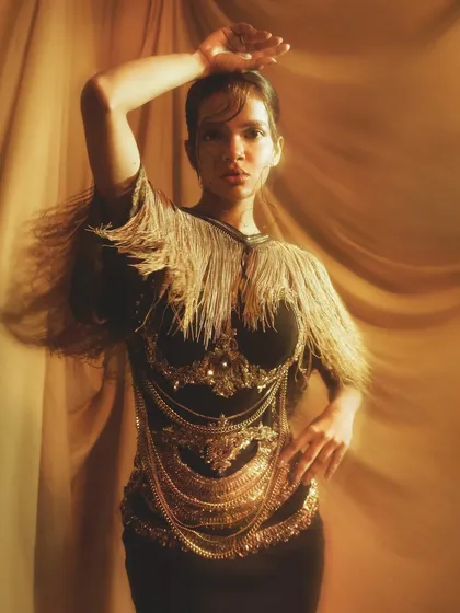 This image captures the fierce energy of the shoot, with the model's pose and the dramatic gold makeup creating a powerful statement.