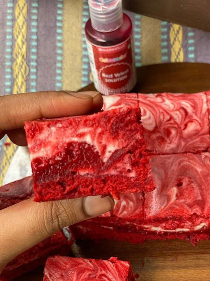 A close-up of the red velvet cheesecake brownie, showing the moist and tender crumb. You can see the rich red color achieved using quality ingredients, swirled with creamy cheesecake filling.