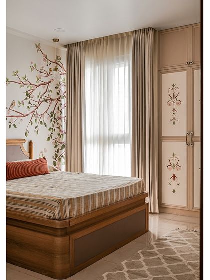 In the parents' bedroom, a delicate floral mural on the wall harmonizes with the custom hand-painted wardrobe shutters. The soft, earthy color palette keeps the space calm and restful.