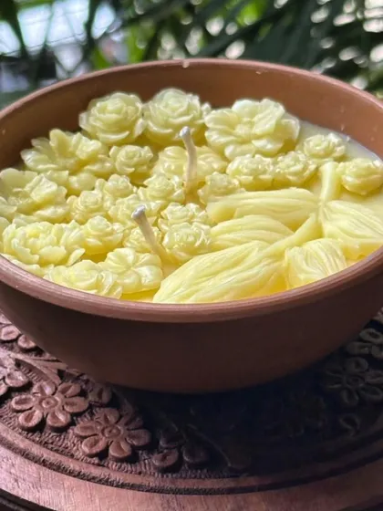 A closer look at the intricate floral details on our Mitti Bowl Candle, placed on a beautifully carved wooden stand. Each flower is hand-poured with organic beeswax, making it a true piece of art before it's even lit.